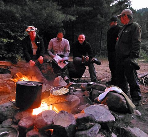 Group of veterans sitting around a camp fire 480x445