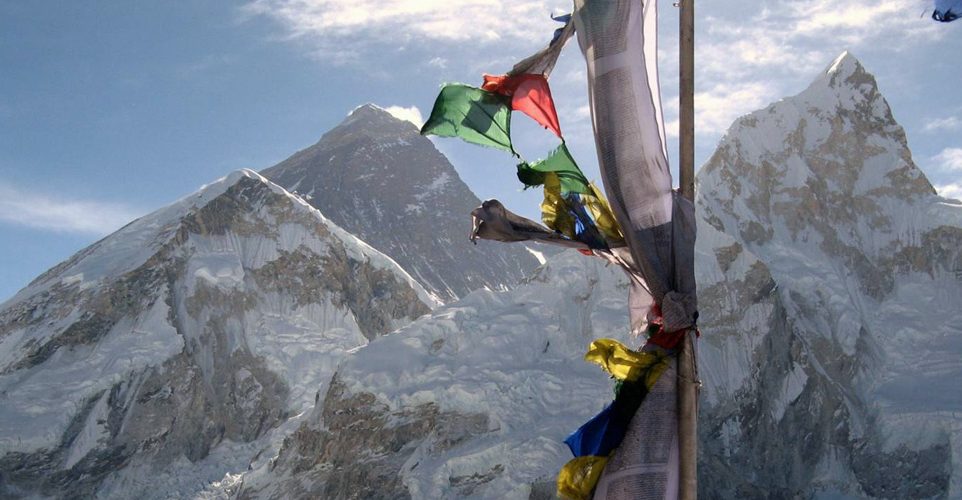Mount Everest in the background with a flag in the front 1 962x500