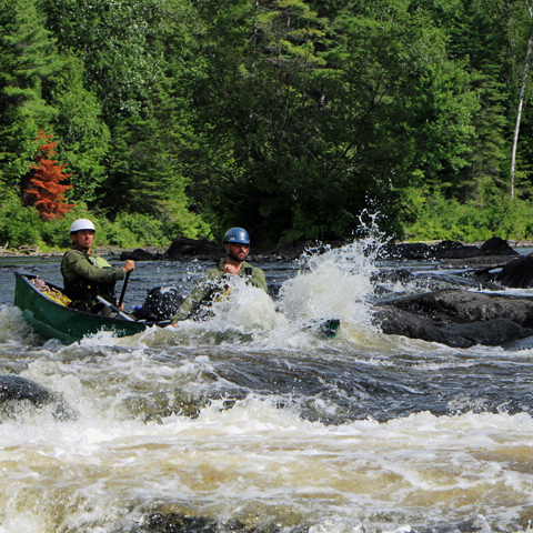 Participants in canoe paddling through white water
