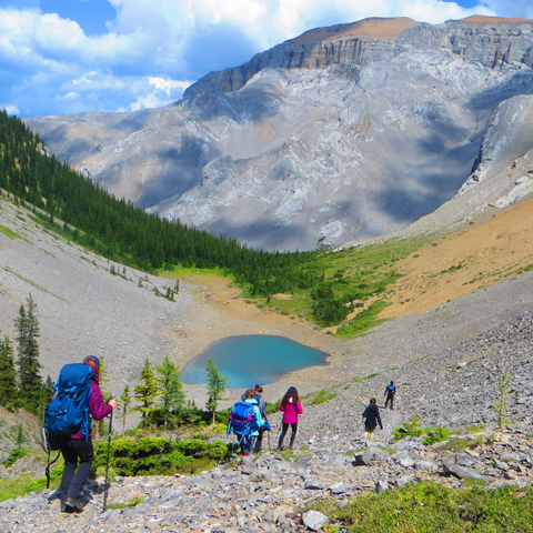 group ascends into a valley with a picturesque glacier pond nearby