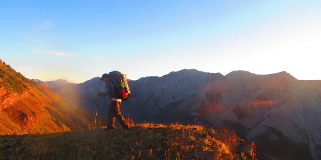 hiker walks along a ridge with mountains behind HEADER 1 640x320