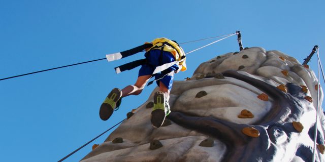 male student coming down from climbing the rock climbing wall 640x320