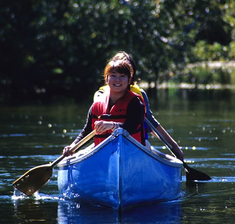 participants paddling a blue canoe smiling 480x459