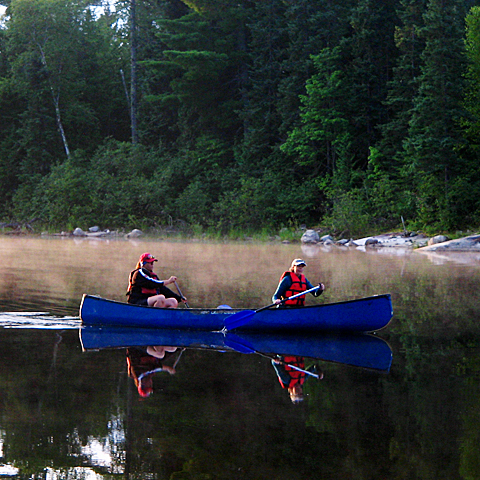 two women of courage paddling a canoe on calm water