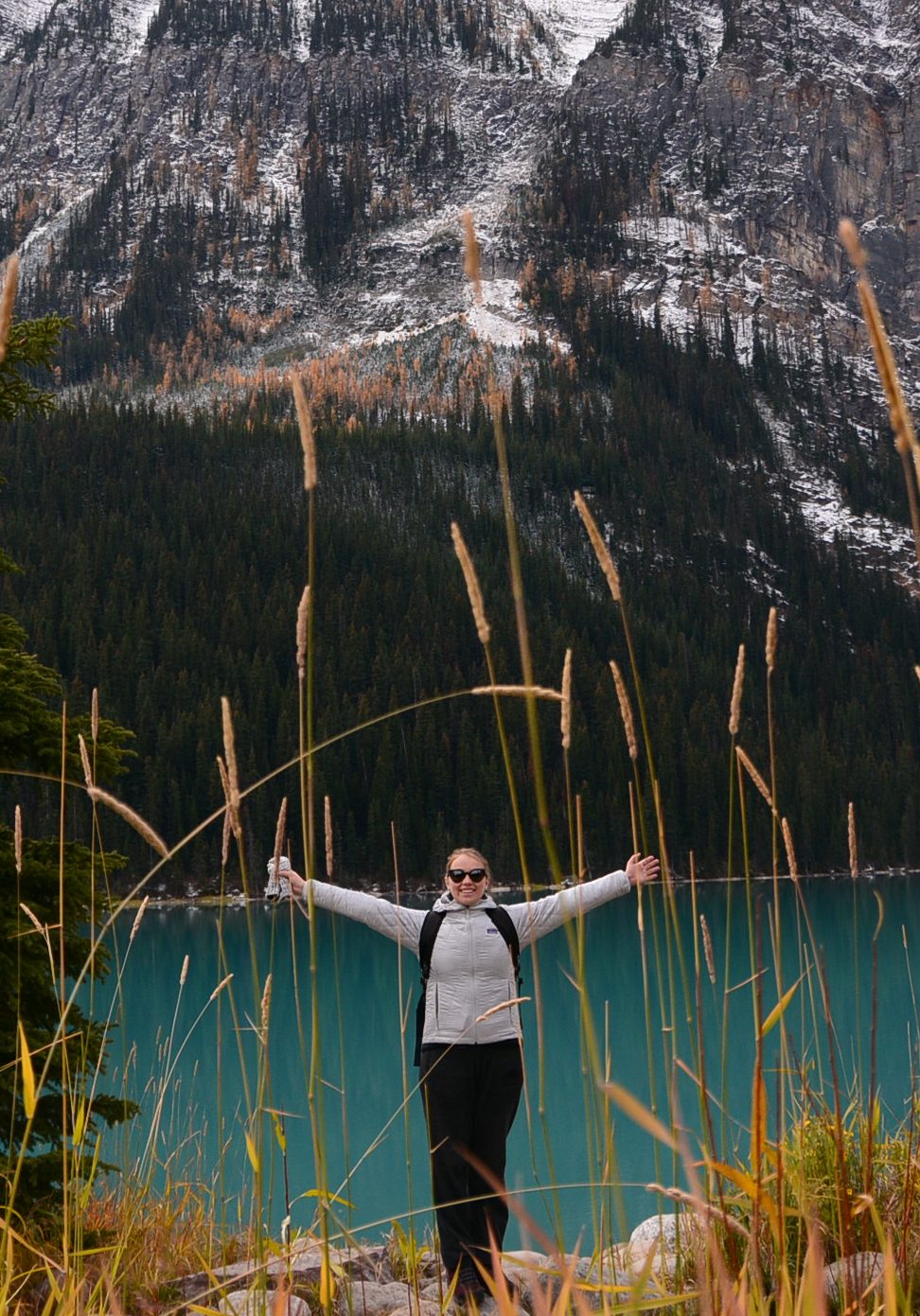 Girl Arms stretched wide by blue lake mountains hiking