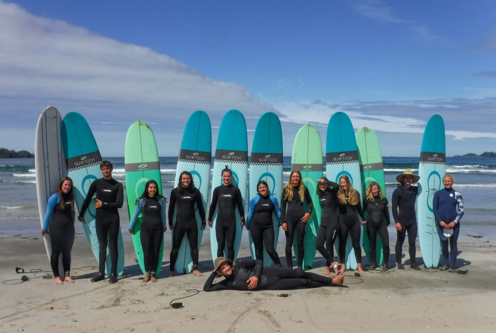 Image of a line of teens standing in front of upright surfboards