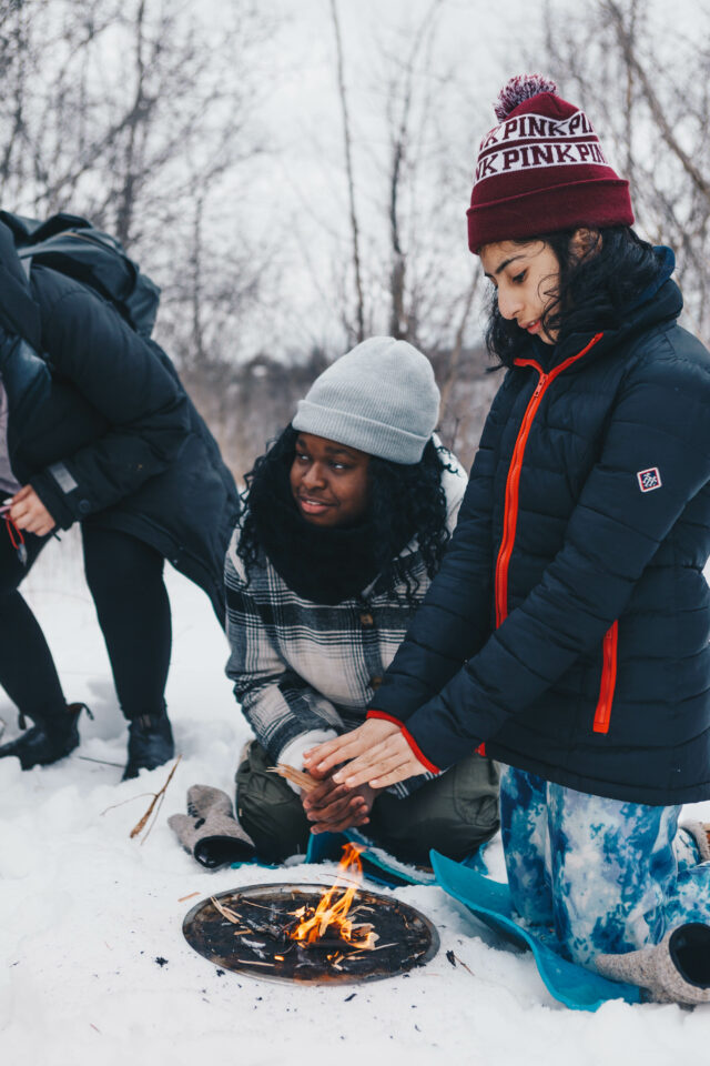 two teens making a fire in the snow