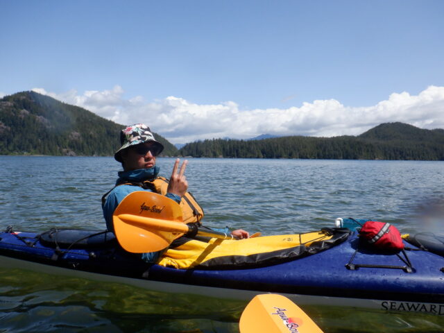 boy posing with peace sign in a canoe on the sea