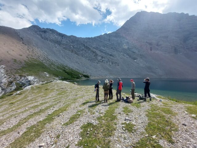 teens walking in a line with mountain and lake behind