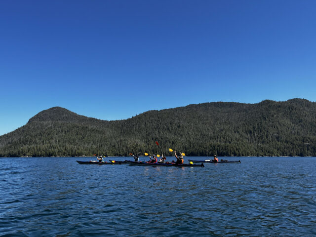 teens kayaking on a lake infront of a mountain