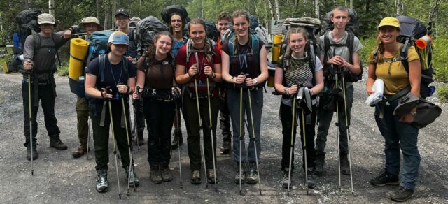 teens in hiking gear smiling on a trail