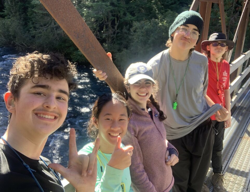 teens smiling and posing for a selfie on a bridge